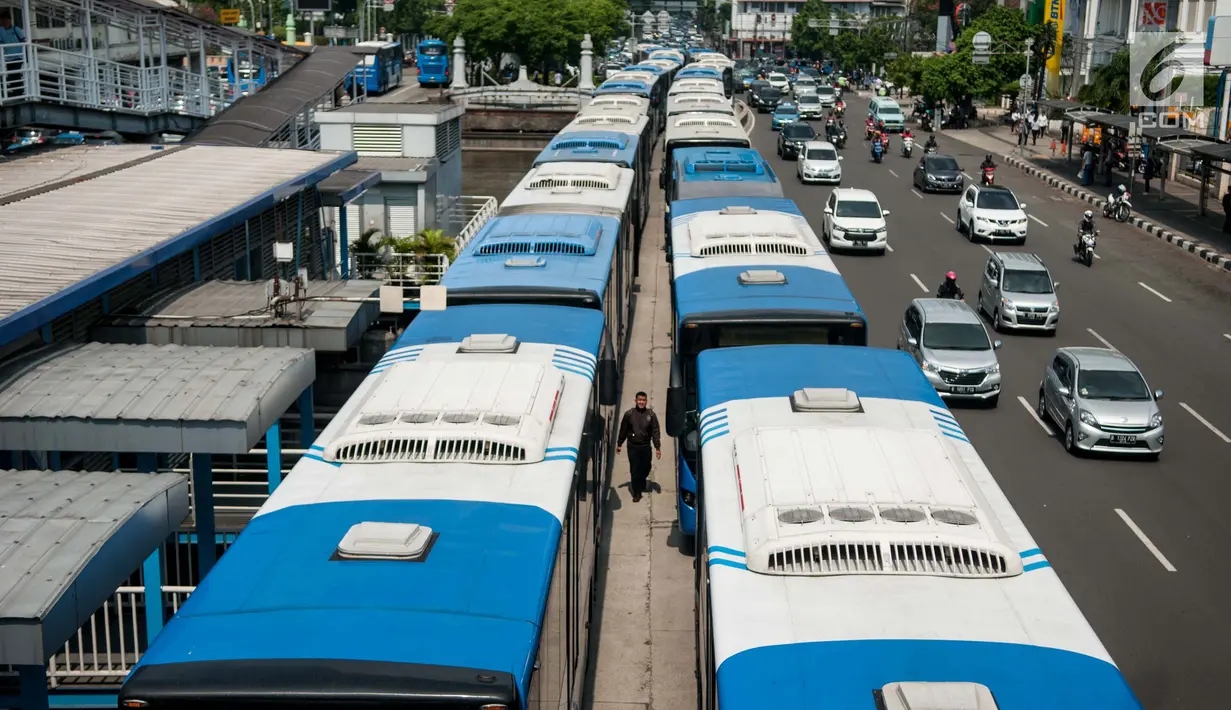 Seorang warga melewati Bus Transjakarta mogok kerja mengantarkan penumpang di Halte Harmoni, Jakarta (12/6). Akibat aksi mogok kerja tersebut, operasional bus Transjakarta menjadi terganggu. (Liputan6.com/Gempur M Surya)