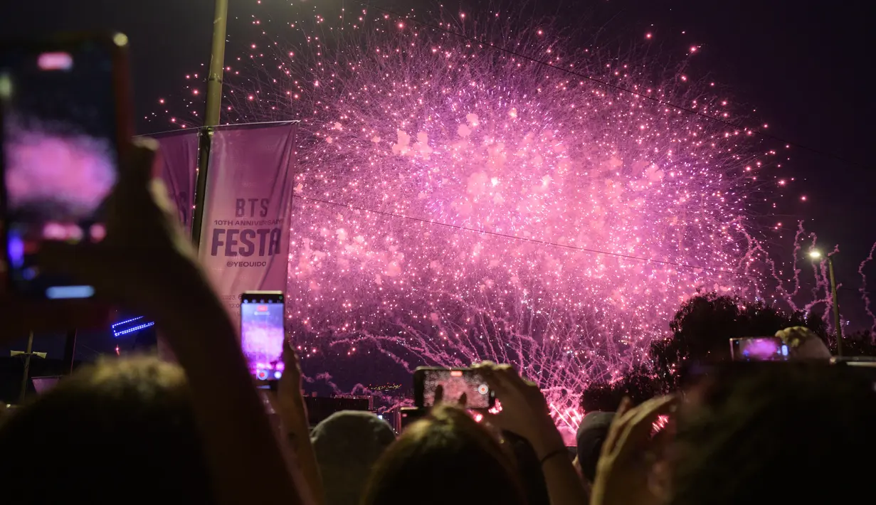 Para penggemar megabintang K-pop BTS menyaksikan pertunjukan kembang api selama "BTS 10th Anniversary FESTA @ Yeouido" di Seoul pada tanggal 17 Juni 2023, untuk menandai ulang tahun ke-10 debut grup tersebut. (ANTHONY WALLACE / AFP)
