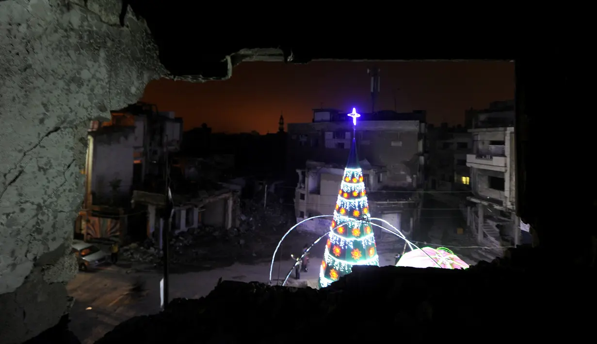 Pohon Natal terlihat dari jendela sebuah bangunan yang hancur akibat serangan di kawasan Al-Hamidiyah kota tua Homs, Suriah, (24/12). (REUTERS/Omar Sanadiki)