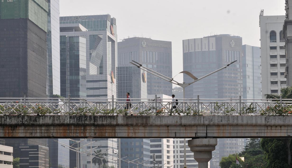 Pejalan kaki melintas di jembatan penyeberangan orang (JPO) yang tidak beratap di jalan Sudirman, Jakarta, Rabu (6/11/2019). Pemprov DKI melalui Dinas Bina Marga mencopot atap JPO Sudirman agar pejalan kaki dapat menikmati pemandangan gedung-gedung pencakar langit. (merdeka.com/Iqbal Nugroho)