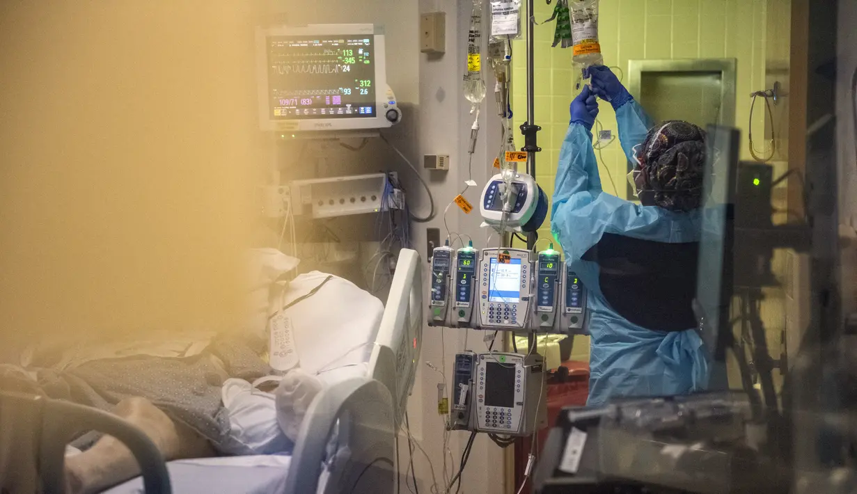 Pekerja medis merawat pasien covid-19 di ruang tekanan negatif di bangsal ICU UMass Memorial Medical Center di Worcester, Massachusetts, Selasa (4/1/2022). Menurut data, Massachusetts saat ini memiliki 2.221 rawat inap pasien covid dengan 402 di kamar ICU dan 245 diintubasi. (Joseph Prezioso/AFP)