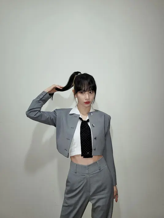 Tampil preppy, SeolA WJSN mengenakan crop top putih berkerah yang ditambah detail dasi bermotif polkadot. Ia juga mengenakan set blazer dan celana bernuansa abu-abu. Foto: Instagram @seola_s.