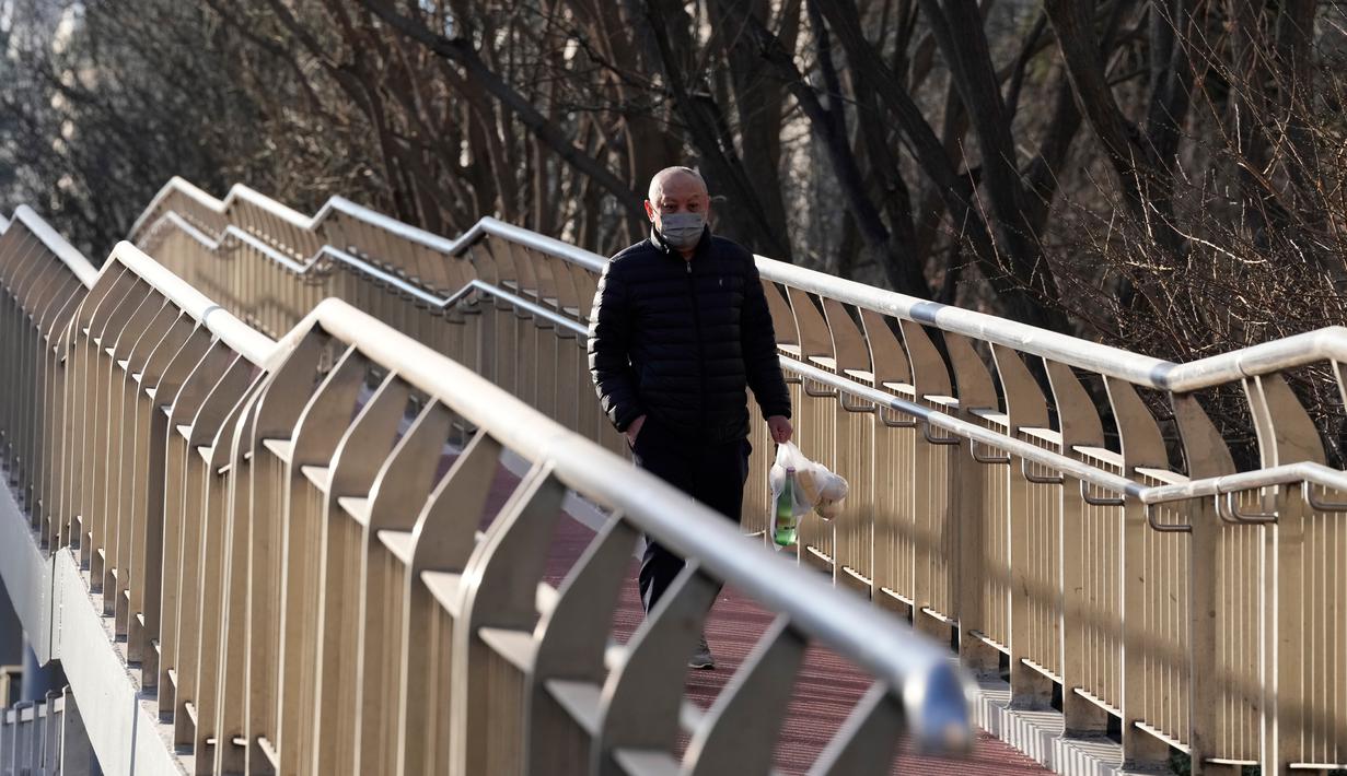 Seorang warga yang mengenakan masker berjalan di jembatan, Beijing, China, Kamis (15/12/2022). Seminggu setelah China melonggarkan beberapa tindakan pengendalian COVID-19 yang paling ketat di dunia, ketidakpastian masih ada mengenai arah pandemi di negara dengan jumlah penduduk terpadat di dunia tersebut. (AP Photo/Ng Han Guan)