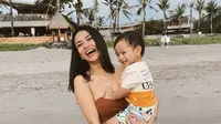Vanessa Angel menggendong putranya, Gala Sky dalam momen liburan di sebuah pantai. (Instagram/@vanessaangelofficial)