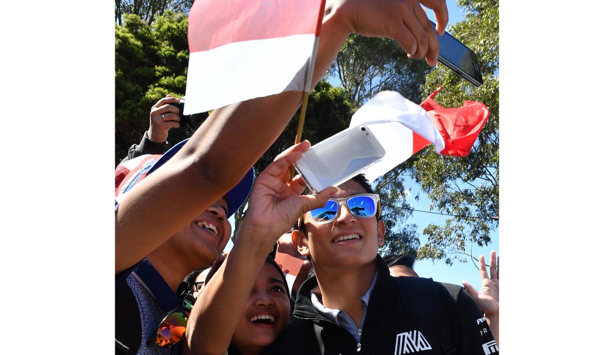 Dengan membawa bendera Merah-Putih fans dari Indonesia berebut foto saat bertemu Rio Haryanto  sebelum balapan perdana Formula One Australian Grand Prix, Melbourne, Minggu (20/3/2016). (AFP/Paul Crock)