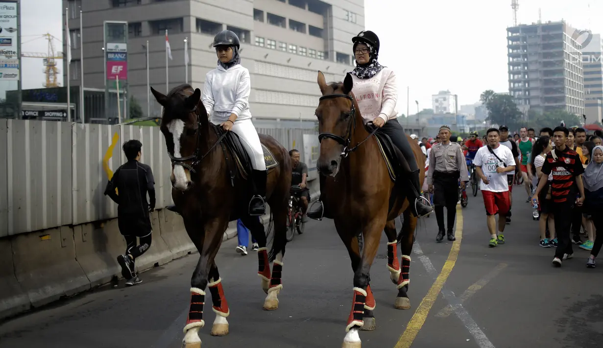 Dua pengunjung berkeliling area car free day  dengan menunggang kuda milik satuan polisi berkuda Polda Metro Jaya di Bundaran HI, Jakarta, Minggu (18/3). Kuda-kuda yang diterjunkan itu menarik perhatian pengunjung. (Liputan6.com/Faizal Fanani)
