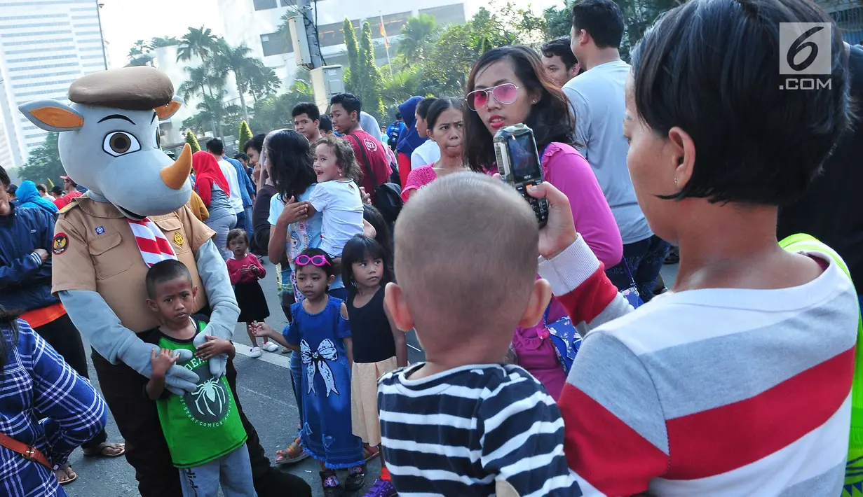 Seorang anak berfoto dengan boneka Pramuka dalam aksi Satu Indonesia di area Car Free Day (CFD), Bundaran HI, Minggu (30/7). Aksi tersebut bertajuk “Satu Nusa, Satu Bangsa, Satu Bahasa, Indonesia”. (Liputan6.com/Helmi Afandi)