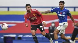 Gelandang Manchester United, Bruno Fernandes, berebut bola dengan gelandang Everton, Allan, pada laga lanjutan Liga Inggris di Goodison Park Stadium, Sabtu (7/11/2020) malam WIB. Manchester United menang 3-1 atas Everton. (Paul Ellis/Pool via AP)