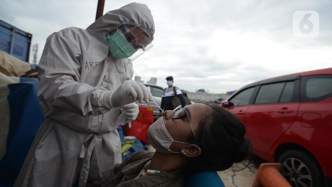 Petugas medis mengambil sampel lendir wisatawan untuk tes usap atau Swab Antigen di Pelabuhan Kali Adem, Jakarta, Kamis (31/12/2020). Pemeriksaan swab antigen wisatawan yang akan libur Tahun Baru di Kepulauan Seribu dilakukan untuk mencegah penyebaran COVID-19. (merdeka.com/Imam Buhori)