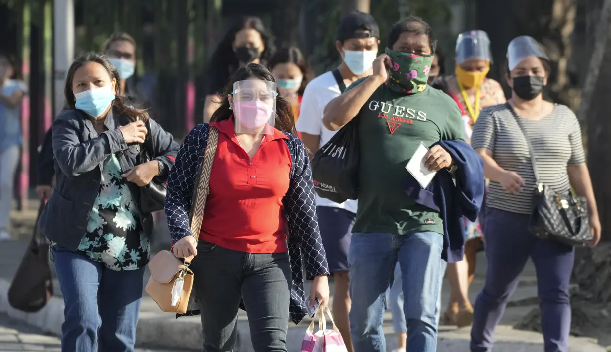 Orang-orang yang memakai masker berjalan di samping jalan di kota Quezon, Filipina, Senin (17/1/2022). Orang-orang yang belum menerima vaksin COVID-19 dilarang naik transportasi publik di ibu kota Manila mulai Senin menyusul lonjakan kasus covid varian omicron. (AP Photo/Aaron Favila)