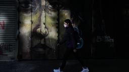 Seorang pejalan kaki memakai masker di pusat kota Santiago, Chili, Rabu (5/4/2022). Chile akan melonggarkan aturan protokol kesehatan Covid-19 pada 14 April dan berhenti mewajibkan penggunaan masker di ruang terbuka. (AP Photo/Esteban Felix)