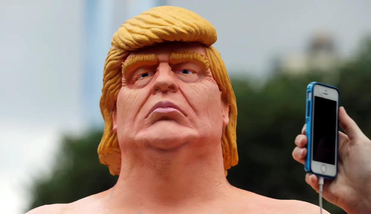 Warga memfoto kepala patung Donald Trump tanpa busana yang dipajang di Union Square Park, AS, Kamis (18/8). Patung Capres AS dari Partai Republik ini juga dipajang di San Francisco, Los Angeles, Cleveland, dan Seattle. (REUTERS/Brendan McDermid)