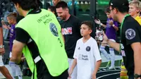 Pemain depan Inter Miami asal Argentina, Lionel Messi (tengah-kiri), dan putranya, pemain U-12 Inter Miami, Thiago Messi (tengah-kanan), tiba di lapangan untuk pertandingan perdana Inter Miami CF Youth International Cup antara Inter Miami U-12 dan Orlando SC U-12 di Chase Stadium di Fort Lauderdale, Florida, pada tanggal 24 Mei 2024. (Chris ARJOON/AFP)