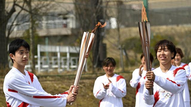 Olimpiade Tokyo 2021: Atlet timnas sepak bola wanita Jepang Azusa Iwashimizu dan siswa SMA Asato Owada menunjukan obor Olimpiade.
