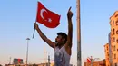 Seorang pria mengibarkan  bendera nasional Turki di Taksim Square, pusat kota Istanbul, Sabtu (16/7). Ratusan warga turun ke jalan merayakan kegagalan kudeta militer di Turki terhadap Pemerintahan Erdogan. (REUTERS/Kemal Aslan)