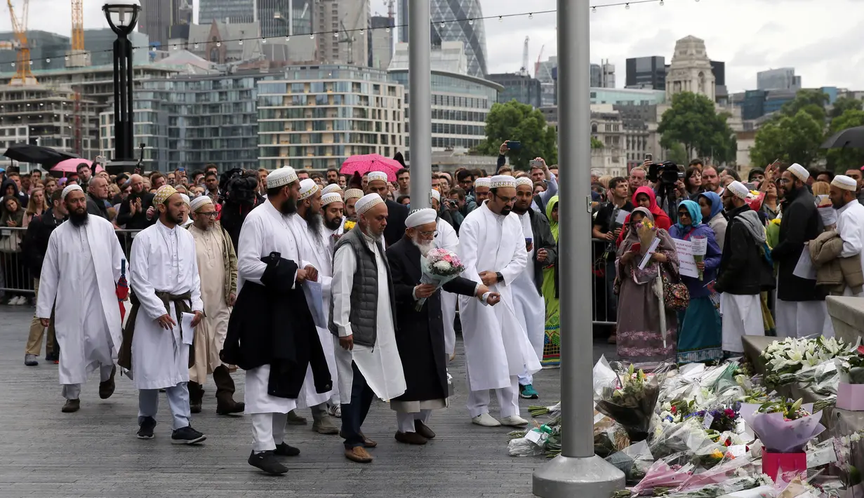 Sejumlah muslim datang membawa karangan bunga di Potters Field Park, London, Senin (5/6). Mereka mengenang dan mendoakan korban serangan teror di London Bridge dan Borough Market yang menewaskan 7 orang dan melukai puluhan lainnya. (AP Photo/Tim Ireland)
