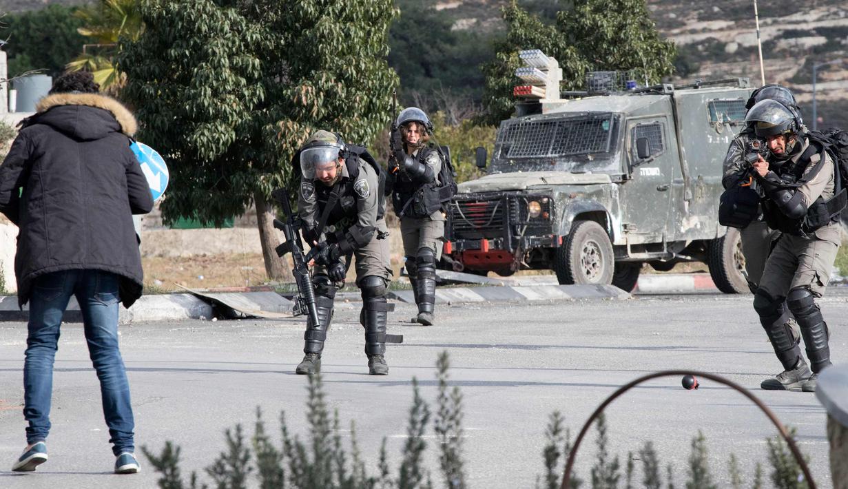 Pasukan keamanan Israel bersiap menembak pria Palestina setelah dia menikam seorang tentara di kota al-Bireh, Tepi Barat yang diduduki Israel (15/12). Pria tersebut membawa pisau dan diduga memegangi benda diduga bom. (AFP Photo/Oren Ziv)