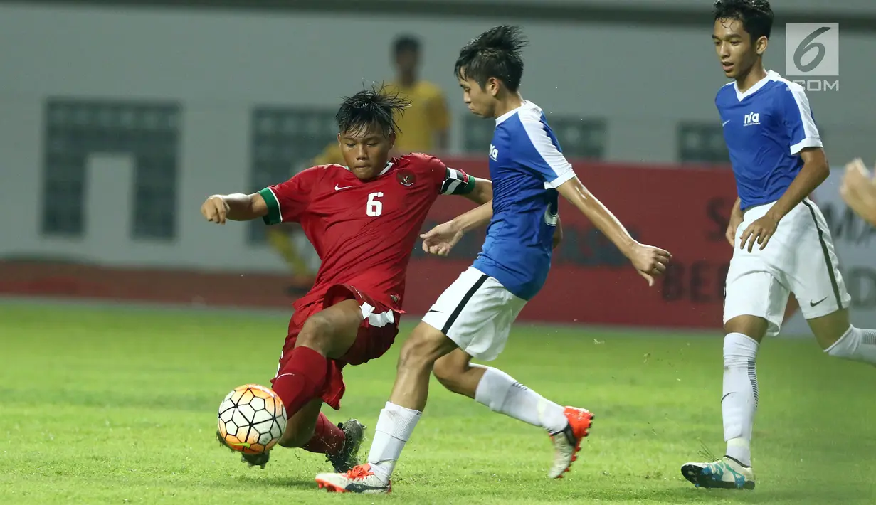 Kapten Timnas Indonesia U-16, Kartika Vedayanto Putra (kiri) mencoba melewati kawalan pemain Singapura U-16 saat laga persahabatan di Stadion Wibawa Mukti, Kab Bekasi, Kamis (8/6). Indonesia U-16 menang telak 4-0. (Liputan6.com/Helmi Fithriansyah)