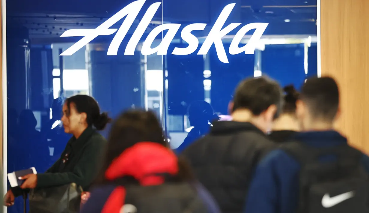 Logo Alaska Airlines ditampilkan saat pelancong berdiri di area check-in Bandara Internasional Los Angeles (LAX) di Los Angeles, California, Senin (8/1/2024). (Mario Tama/Getty Images/AFP)