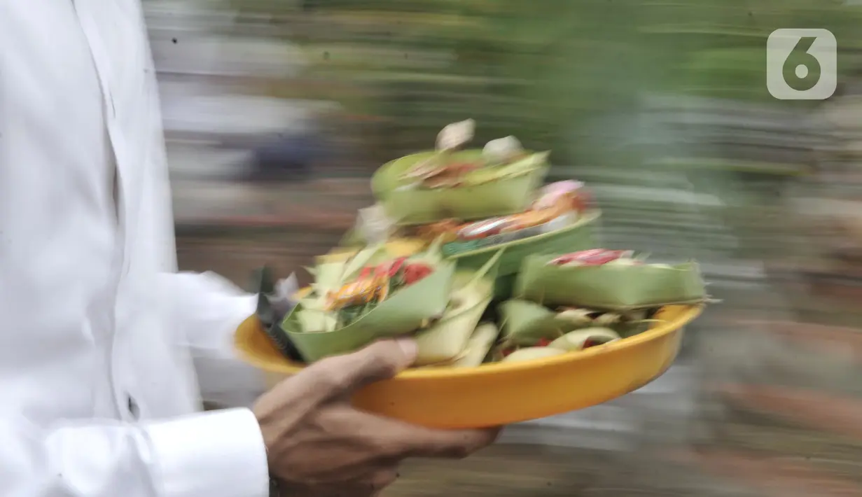 Umat Hindu membawa sesajen saat persembahyangan Hari Raya Galungan di Pura Aditya Jaya, Rawamangun, Jakarta, Rabu (19/2/2020). Hari Raya Galungan yang merupakan hari kemenangan kebenaran (Dharma) atas kejahatan (Adharma) itu dirayakan setiap 210 hari sekali. (merdeka.com/Iqbal Nugroho)