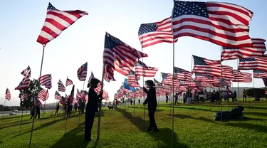 Orang-orang membantu pengibaran bendera AS untuk peringatan 20 tahun serangan 9/11 di Pepperdine University di Malibu, California, Rabu (8/9/2021). Selama 14 tahun, universitas itu memperingati tragedi 11 September 2001 dengan mengibarkan sekitar 3.000 bendera Amerika. (Frederic J. BROWN/AFP)