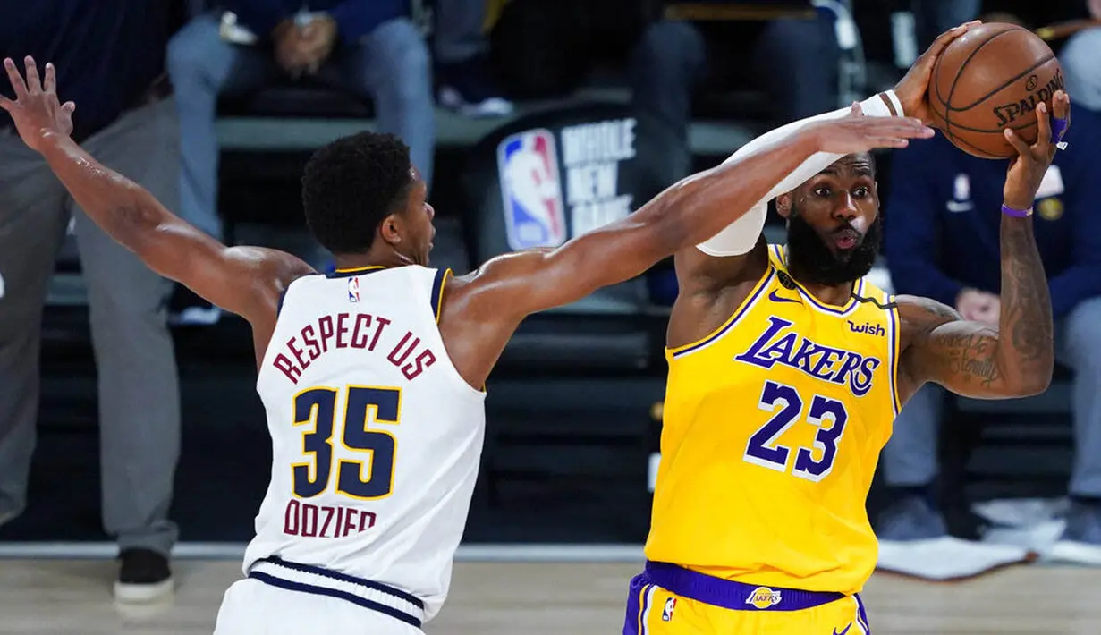 Pebasket Los Angeles Lakers, LeBron James, berusaha melewati hadangan pemain Denver Nuggets, PJ Dozier, pada laga NBA di The Arena, Senin (11/8/2020). LA Lakers menang dengan skor 124-121. (AP Photo/Ashley Landis, Pool)