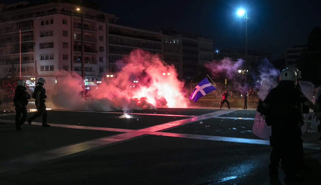 Polisi Yunani mengamankan area ketika pengunjuk rasa antivaksin melemparkan suar dan bom molotov selama rapat umum di alun-alun Syntagma, Athena tengah (24/7/2021). Pengunjuk rasa menentang vaksinasi wajib bagi para pekerja, seperti staf tenaga kesehatan dan perawat. (AP Photo/Yorgos Karahalis)