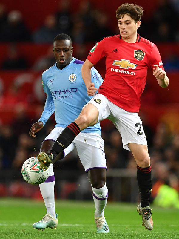Bek Manchester City, Benjamin Mendy (kiri) berusaha merebut bola yang dibawa gelandang Manchester United, Daniel James pada pertandingan leg pertama semifinal Piala Liga Inggris di Old Trafford (7/1/2020). City menang 3-1 atas MU. (AFP/Paul Ellis)
