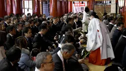 Seorang imam Shinto dan gadis Shinto memberikan "tamagushis" kepada pengusaha selama upacara awal tahun  di Kuil Kanda Myojin, Tokyo (4/1). (AFP Photo/Toshifumi Kitamura)