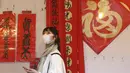 Seorang wanita memakai masker untuk mencegah penyebaran virus corona berjalan melalui lorong-lorong yang dihias dekorasi Imlek di sepanjang pasar Jalan Dihua di Taipei, Taiwan, Rabu (10/2/2021).  (AP Photo/Chiang Ying-ying)