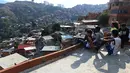 Sejumlah musisi menikmati pemandangan di permukiman kumuh Petare di Caracas pada 19 Mei 2019. Petare yang merupakan kawasan kumuh terbesar di Venezuela menjadi rumah bagi lebih dari 500.000 jiwa. (Photo by MARVIN RECINOS / AFP)