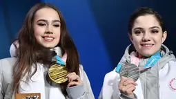 Alina Zagitova (kiri) dan Evgenia Medvedeva dari Rusia tersenyum di atas podium usai pertandingan figure skating putri Olimpiade Musim Dingin Pyeongchang 2018 di Pyeongchang Medals Plaza (23/2). (AFP Photo/Dimitar Dilkoff)
