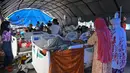 Orang-orang yang terluka dalam gempa dengan magnitudo 6,2 beristirahat di tempat penampungan sementara di luar Rumah Sakit Regional Sulbar, Mamuju, Sulawesi Barat, Minggu (17/1/2021). Mereka dirawat di dalam tenda darurat untuk mengantisipasi gempa susulan. (ADEK BERRY/AFP)