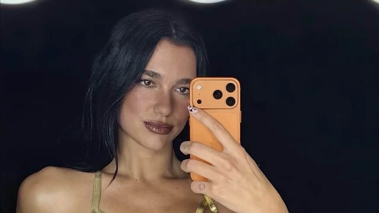 Dua Lipa saat selfie pakai iPhone 17 Pro Orange pakai korset warna gold. [@apple/@dualipa]