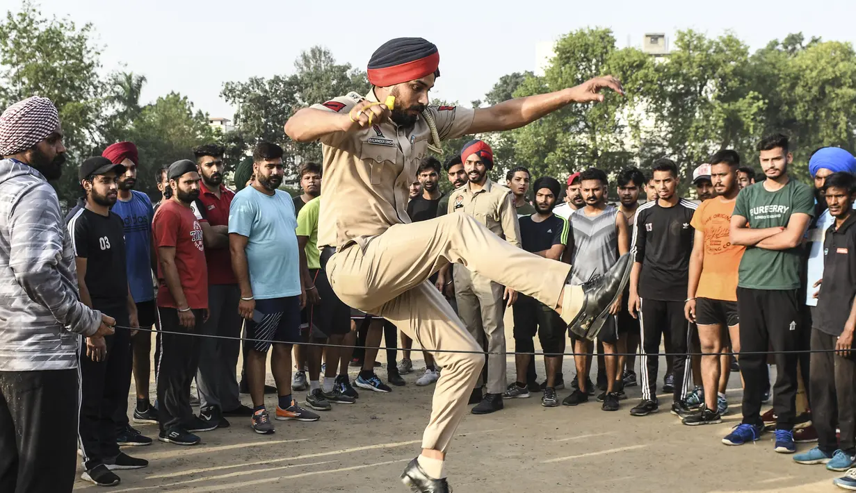 Polisi Punjab melompat saat membimbing pemuda selama pelatihan untuk menjadi Polisi Punjab, di Amritsar (28/6/2021). Polisi Punjab memiliki beragam layanan khusus, termasuk pencegahan dan pendeteksian kejahatan, pemeliharaan hukum dan ketertiban, serta penegakan Konstitusi India. (AFP/Narider Nanu)