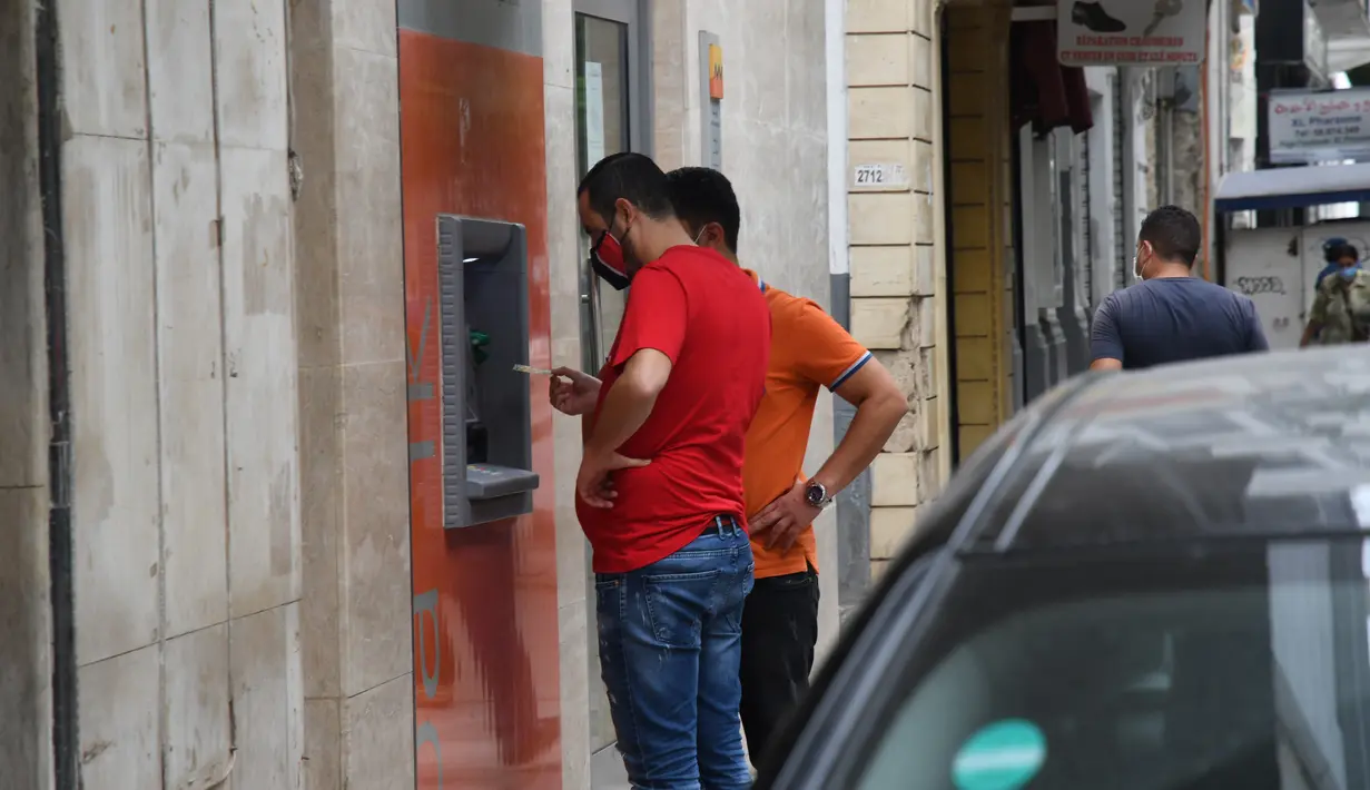 Orang-orang yang mengenakan masker menarik uang di sebuah mesin ATM di Tunis, Tunisia, pada 5 Oktober 2020. Perdana Menteri Tunisia Hichem Mechichi pada 3 Oktober mengumumkan serangkaian langkah untuk membatasi penyebaran cepat COVID-19 di negara tersebut. (Xinhua/Adel Ezzine)