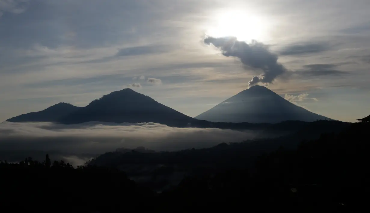 Gunung Agung mengembuskan asap saat matahari terbit (sunrise) terlihat dari Kintamani, Bali, Rabu (13/12). Visual Gunung Agung tampak cerah, asap yang keluar dari kawah gunung itu masih rutin keluar meski tidak secara menerus. (AP Photo/Firdia Lisnawati)