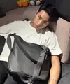 Mingyu dari Seventeen mengenakan tas Dior koleksi Vertical Hobo Bag. Ia memadukannya dengan kaos putih dipadukan celana hitam. [Dior]