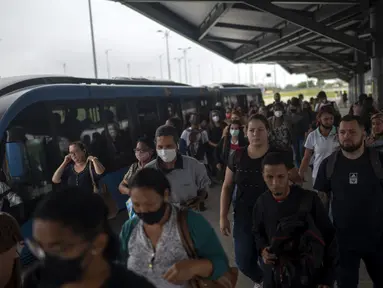 Para komuter berjalan di stasiun BRT Recreio pada hari pertama pencabutan aturan wajib masker di luar ruangan, di Rio de Janeiro, Brasil, Kamis (28/12/2021). Pencabutan aturan wajib masker ini efektif berlaku pada Kamis (28/10) waktu setempat. (MAURO PIMENTEL / AFP)