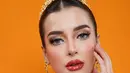 Wajah Tasya dirias dengan gaya makeup Thai yang identik dengan kulit wajah flawless, efek glowing, dan detail mata yang tegas namun feminin. Alis diarsir tebal dan terdefinisi dengan sempurna, sementara riasan mata diperkaya dengan eyeliner tajam dan bulu mata lentik dramatis. [@tasyafarasya].