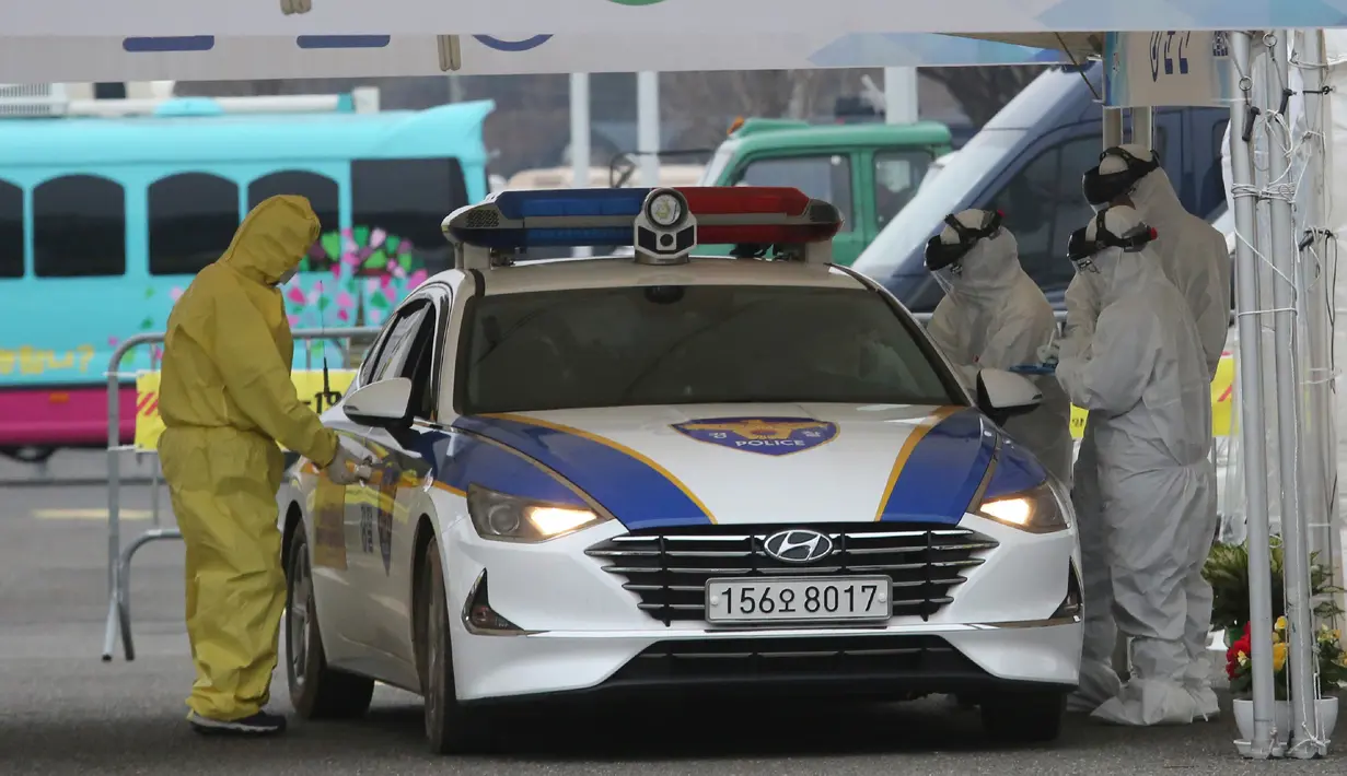 Petugas medis dengan pakaian pelindung mengambil sampel dari pengemudi di layanan "drive-thru" di Goyang, Korea Selatan, 1 Maret 2020. Drive thru (tanpa turun) virus Corona COVID-19 diberlakukan karena permintaan layanan tes kesehatan melonjak.  (AP/Ahn Young-joon)