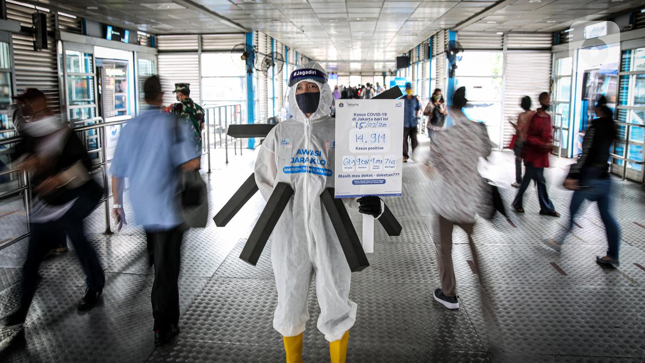 FOTO: Aksi Manusia Covid Ingatkan Jaga Jarak di Halte Transjakarta