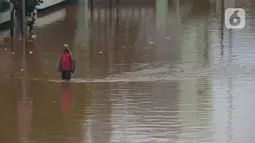 Warga melintasi banjir di Jalan Raya Daan Mogot, Jakarta, Rabu (1/1/2020).  Hujan yang turun saat malam pergantian tahun baru 2019-2020 menyebabkan sejumlah titik jalan terputus di kawasan Grogol terendam banjir. (merdeka.com/Imam Buhori)