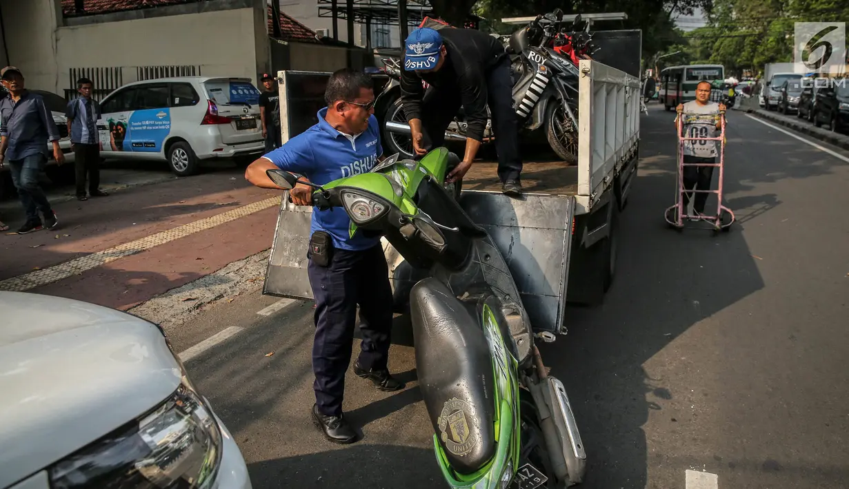 Petugas Dishub mengangkut sepeda motor ke atas truk selama penertiban parkir liar di trotoar kawasan KH Wahid Hasyim, Jakarta, Selasa (1/8). Penertiban dalam rangka Bulan Patuh Trotoar itu untuk mengembalikan fungsi trotoar. (Liputan6.com/Faizal Fanani)