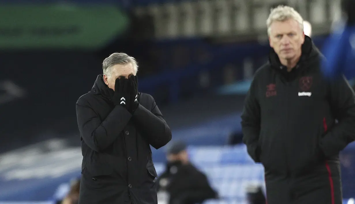 Pelatih Everton, Carlo Ancelotti (kiri) menutup wajahnya saat menyaksikan pemainnya bertanding melawan West Ham pada pertandingan lanjutan Liga Inggris di Goodison Park, Sabtu (2/1/2021). Everton tumbag atas West Ham 0-1. (Jan Kruger, Pool via AP)