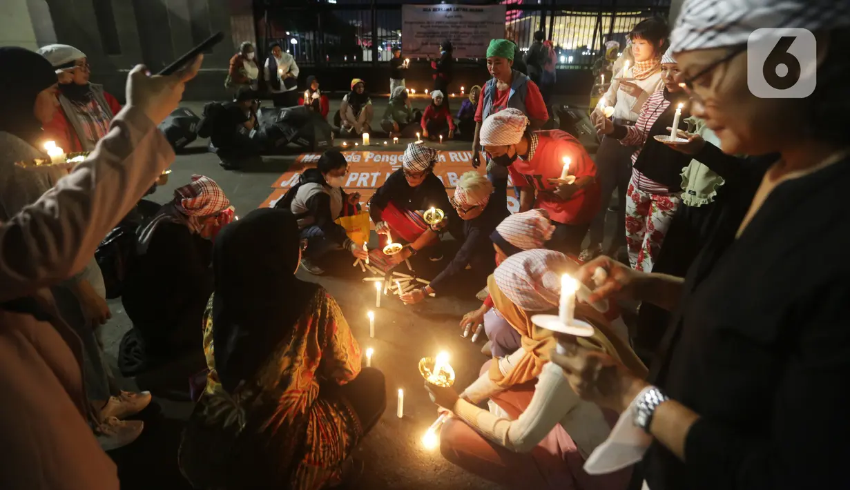 Massa menggelar aksi dengan membawa lilin dan doa bersama lintas agama di depan Gedung DPR, Jakarta, Kamis (16/3/2023). Dalam aksinya, mereka menuntut agar pimpinan DPR menetapkan RUU PPRT sebagai RUU INISIATIF DPR di Rapat Paripurna pada Selasa, 21 Maret 2023 mendatang. (Liputan6.com/Johan Tallo)