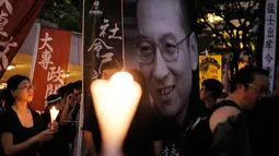 Massa membawa poster bergambar penerima Nobel Perdamaian, Liu Xiaobo, untuk mengenang kematian tokoh pro demokrasi itu di Hong Kong, Sabtu (15/7). Liu Xiaobo meninggal dunia pada Kamis lalu akibat penyakit kanker hati stadium lanjut. (AP Photo/Vincent Yu)