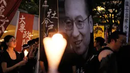 Massa membawa poster bergambar penerima Nobel Perdamaian, Liu Xiaobo, untuk mengenang kematian tokoh pro demokrasi itu di Hong Kong, Sabtu (15/7). Liu Xiaobo meninggal dunia pada Kamis lalu akibat penyakit kanker hati stadium lanjut. (AP Photo/Vincent Yu)