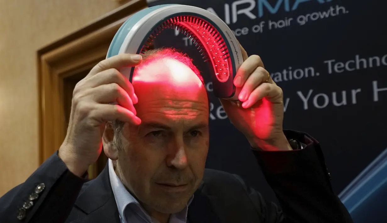 Seorang repoter televisi BBC mencoba alat bernama HairMax Laserband selama acara pembukaan Consumer Electronics Show di Las Vegas. (4/1). Alat ini jika dipakai mampu mengobati kerontokan rambut. (REUTERS / Rick Wilking)