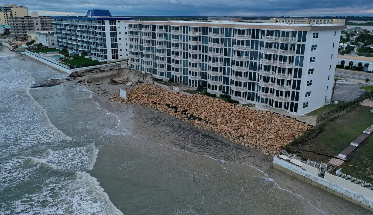 Dalam tampilan udara ini, tembok laut di sepanjang bangunan kondominium terlihat terhantam Badai Nicole di Pantai Daytona, Florida (10/11/2022). Badai Nicoler datang ke darat sebagai badai Kategori 1 sebelum melemah menjadi badai tropis saat bergerak melintasi negara bagian. (Joe Raedle/Getty Images/AFP)
